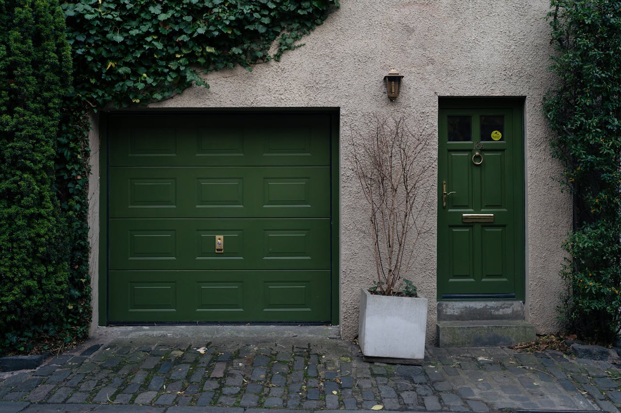Elegant green door and garage in Edinburgh with climbing ivy creating a serene facade.