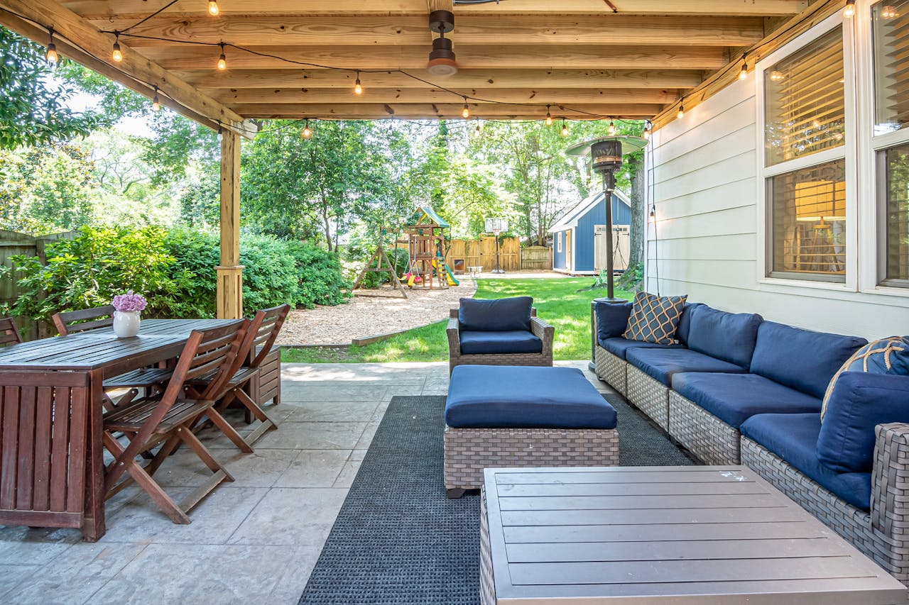 A charming backyard patio featuring cozy seating and a wooden dining set, perfect for outdoor relaxation.