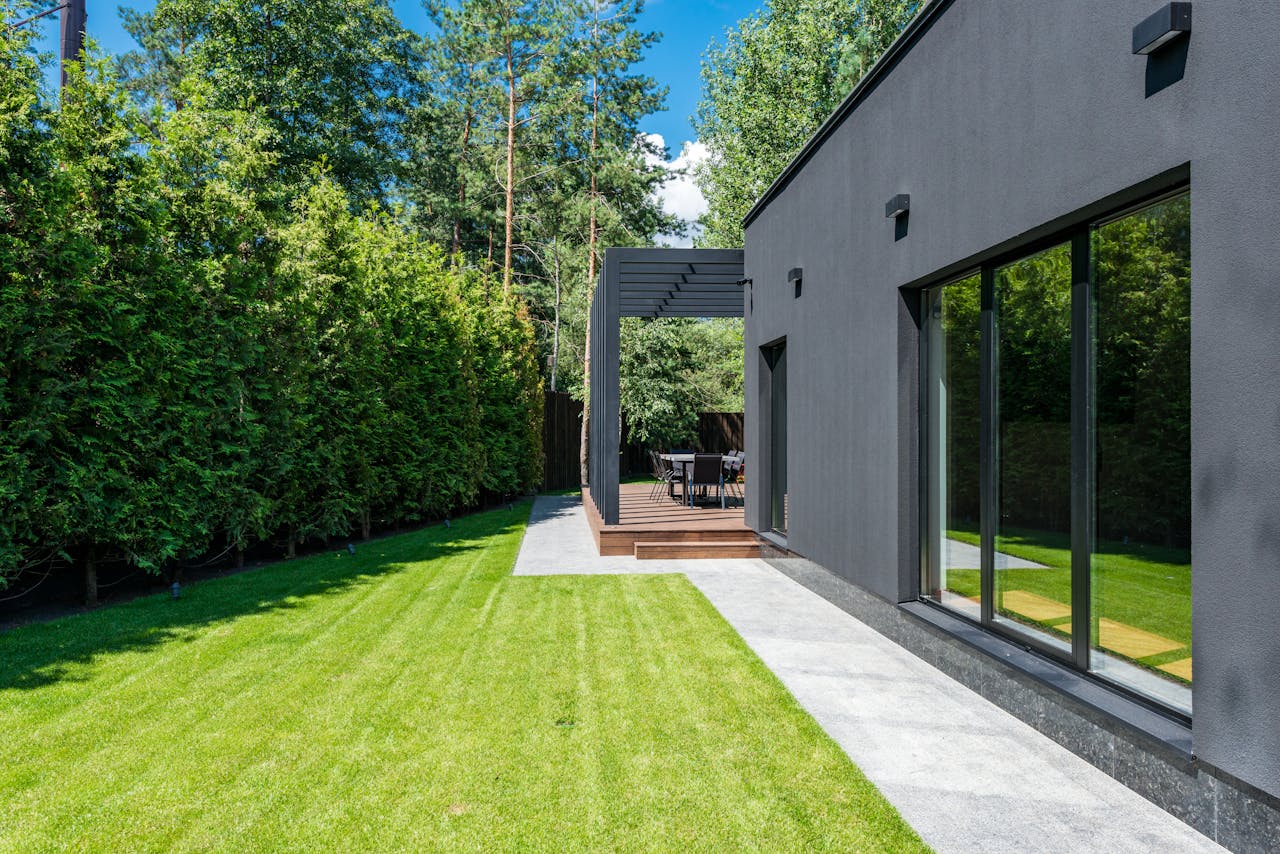 Stylish modern house exterior with a lush green yard and outdoor seating area.